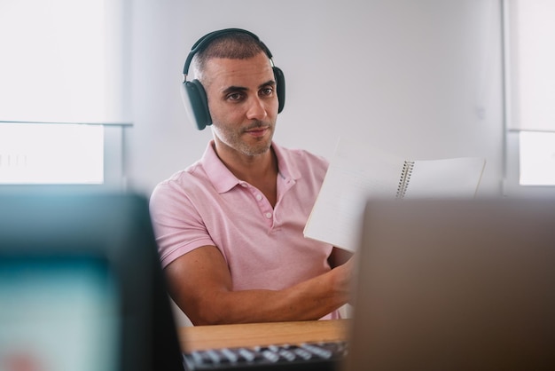 Imprenditore uomo d'affari concentrato con laptop e cuffie professionista maschio che utilizza il computer seduto alla scrivania dell'ufficio di casa libero professionista lavoratore impegnato che lavora su un moderno dispositivo notebook tecnologico