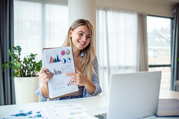 Donna d'affari concentrata che presenta grafici e grafici durante la videochiamata online giovane donna d'affari che ha una chiamata in conferenza con il cliente sul laptop giovane donna che spiega come funzionano gli affari