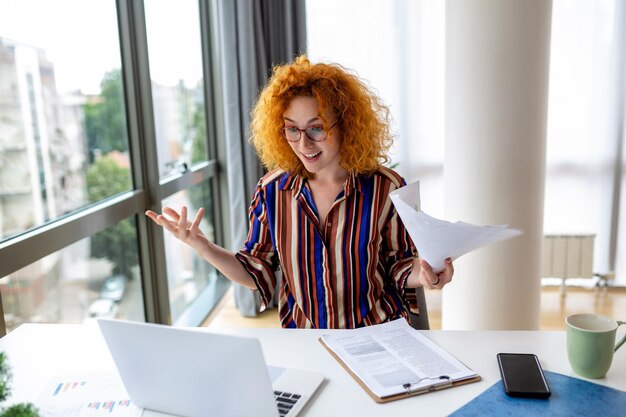 Photo focused business woman using laptop at home looking at screen chatting reading or writing email sitting on couch female student doing homework working on research project online