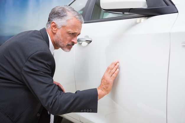 Focused businessman looking at the car body