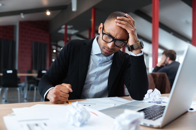 Uomo d'affari concentrato che pensa al laptop