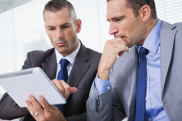 Focused businessmen analyzing documents on their tablet