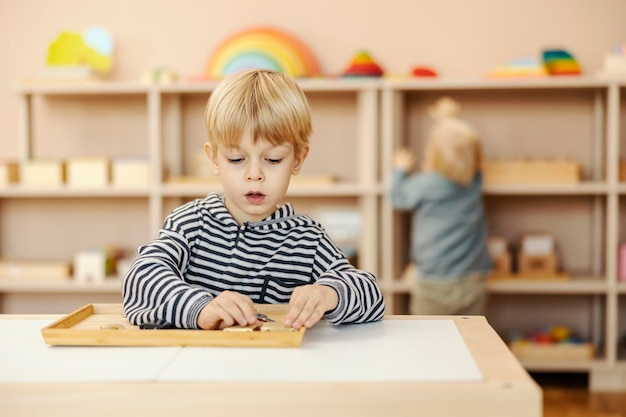 A focused child is sitting at kindergarten and learning through the game