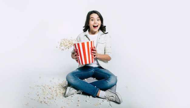 Il bambino concentrato è seduto nella posizione del loto e mangia popcorn, mentre guarda cartoni animati o film.