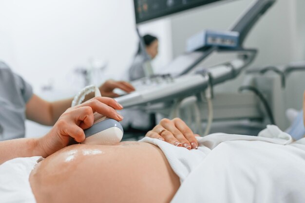 Photo focused close up view pregnant woman is lying down in the hospital doctor does ultrasound
