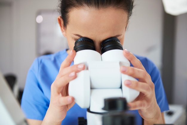 Сосредоточенный стоматолог смотрит в микроскоп