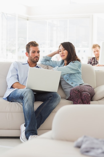 Focused designers working together on laptop on the couch