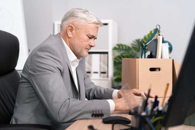 Focused elderly company executive sits in front of computer\
monitor taps fingers on keyboard