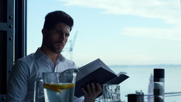 Focused entrepreneur looking cafe dinner menu on cozy restaurant terrace