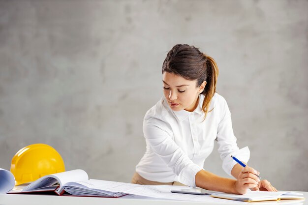 A focused female architect doing calculations for project in office