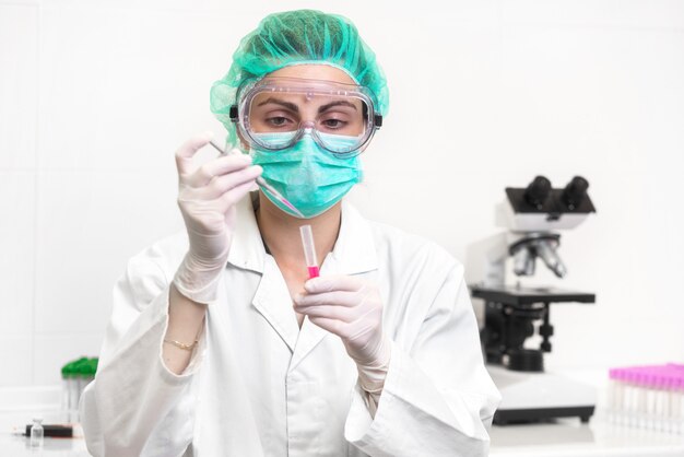 focused female scientist in protective eyeglasses, mask and gloves 