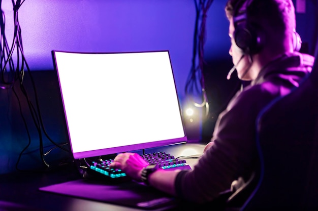 A focused gamer playing video games on computer in gaming room