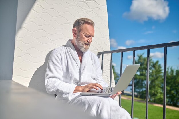 Focused gentleman with the laptop sitting outdoors