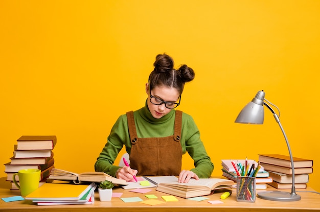 focused girl sit table write copybook over yellow color background