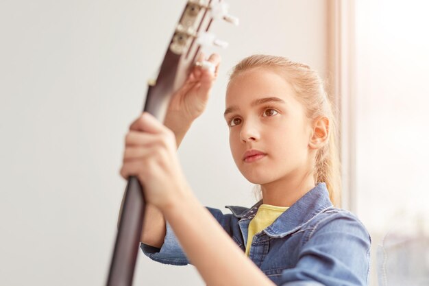 Foto ragazza messa a fuoco che accorda la chitarra