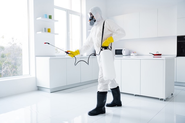 focused guy cleaner in coverall spray kitchen