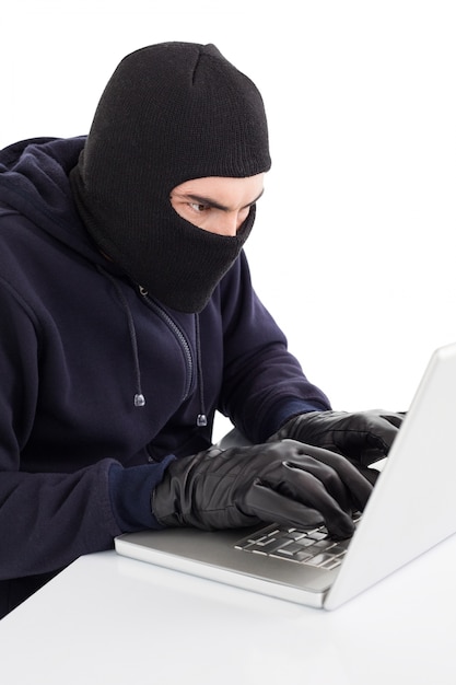 Сосредоточенный хакер в ноутбуке с взломом balaclava