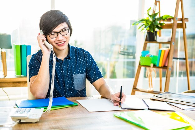 Focused hipster businessman writing in office