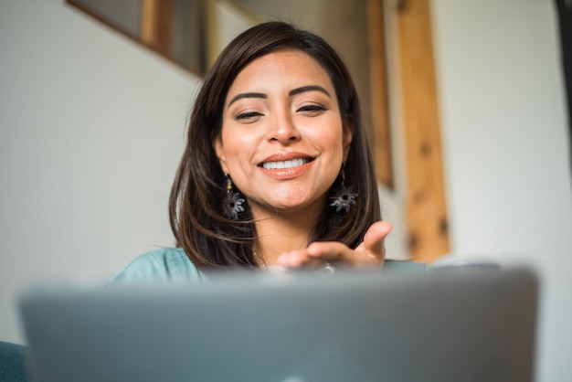 Сосредоточенная латинская женщина улыбается во время семейного видеозвонка