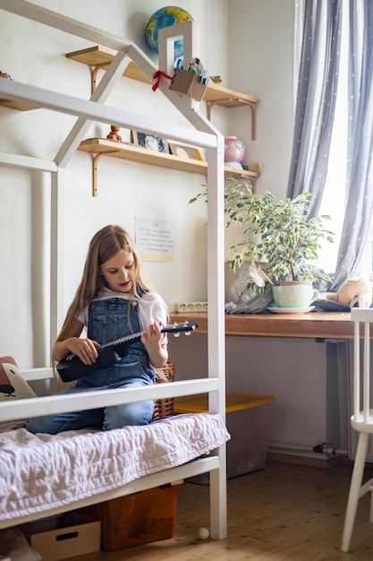 Focused little girl playing melody on ukulele practicing musical exercise enjoying study educational