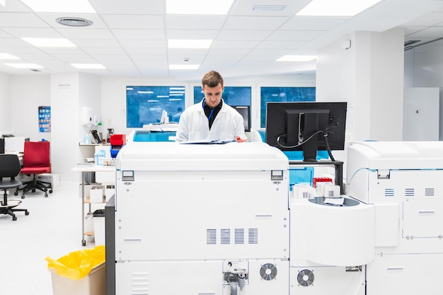 Focused male lab technician checking documents on clinical machinery