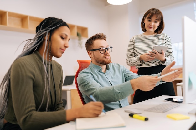 Foto mentore maschile focalizzato o direttore esecutivo capo che insegna diverse intern donne che spiegano il lavoro