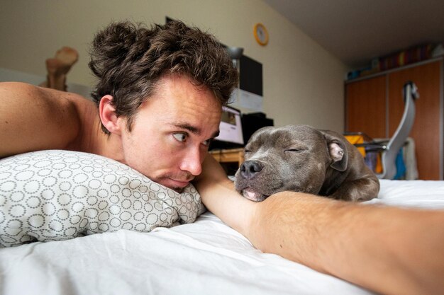 Focused male owner with dog on bed in apartment