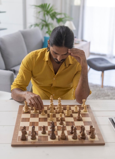 Focused man playing chess at home