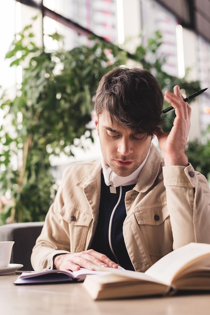 カフェで本を読み、ペンを持っている集中した男