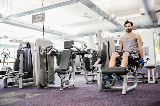 Focused man using weights machine for legs at the gym