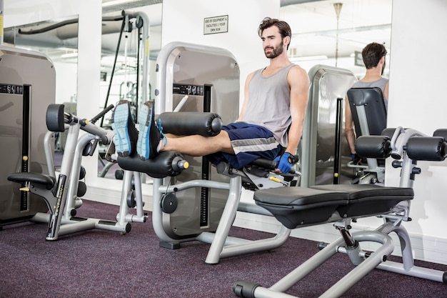 Focused man using weights machine for legs at the gym