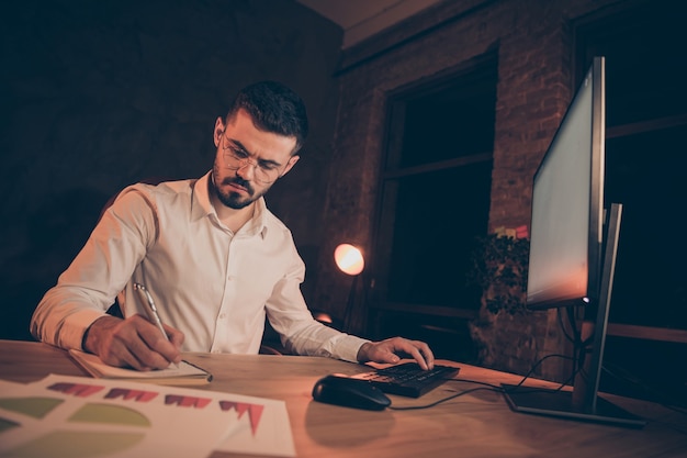 focused man write notebook typing pc