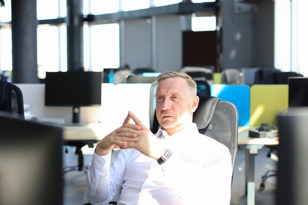 Focused mature businessman deep in thought while sitting at a table in modern office.