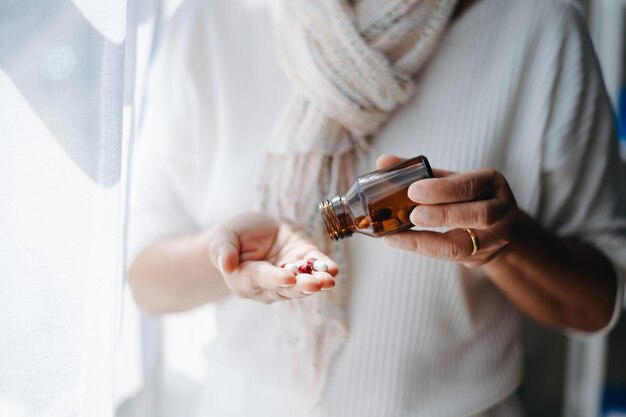 Photo focused mature lady examining drug prescription label at home holding bottle with pills in hands reading instruction to medicine