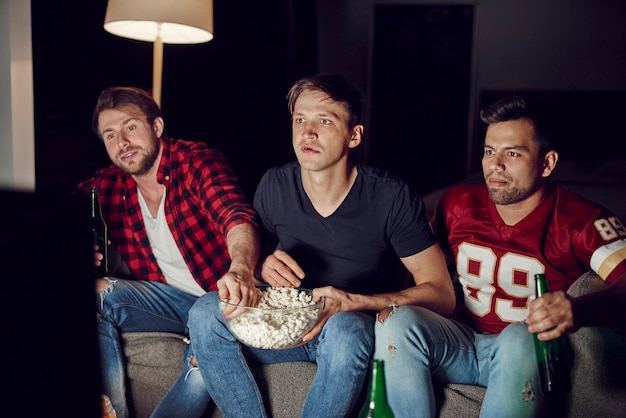 Focused men watching footaball match in the evening