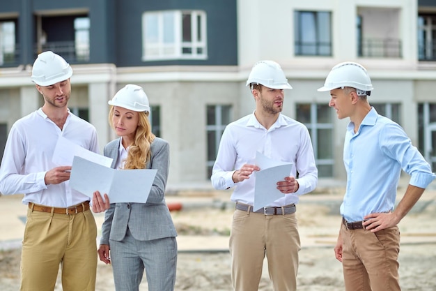 Ispettore femminile di mezza età concentrato che ispeziona i piani di costruzione