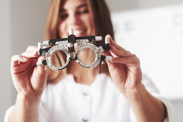 Focused photo. Female doctor showing the little phoropter by holding it in two hands.