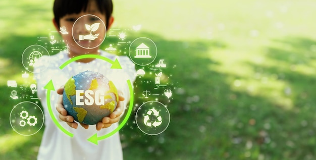 Фото Фокусированный на планете земля глобус с экологически чистой иконой, удерживаемый маленьким мальчиком, символизирует защиту окружающей среды для будущих поколений с помощью усилий esg и зеленых устойчивых технологий panorama reliance
