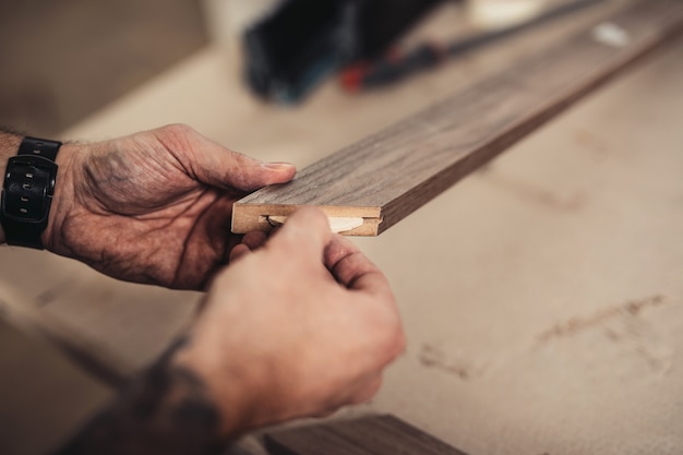 Focused professional carpenter working in his workshop, woodworking and craftsmanship concept.