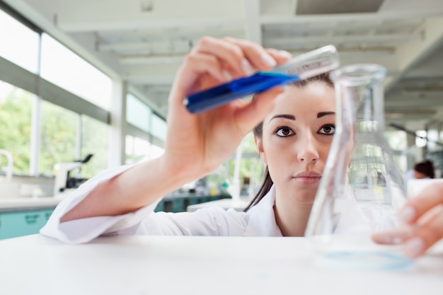 Focused science student pouring liquid