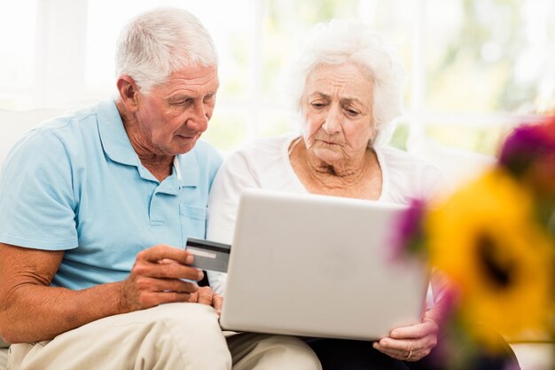 Focused senior couple using laptop at home