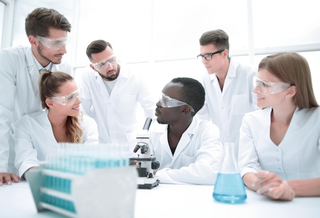 Foto chimici femminili e maschili concentrati e seri in camici da laboratorio e occhiali di sicurezza che fanno esperimenti