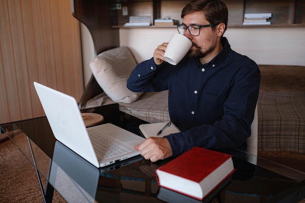 Focused serious male student using laptop looking at computer screen