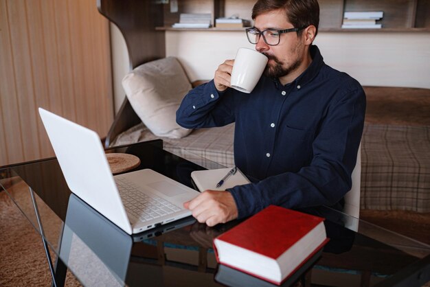 Focused serious male student using laptop looking at computer screen