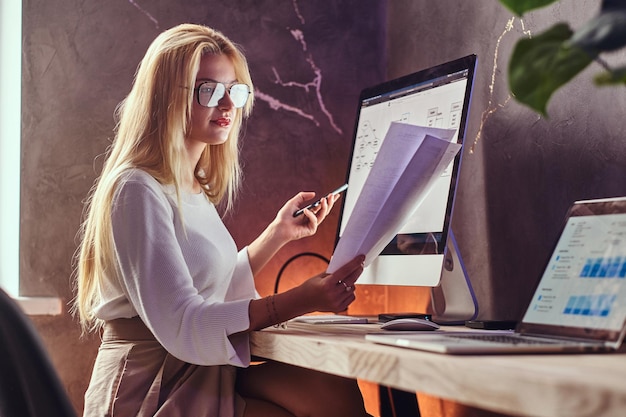 Focused smart businesswoman is reading important document while sitting at her office.