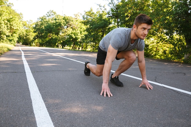 道路で走り始める準備ができている集中スポーツマン