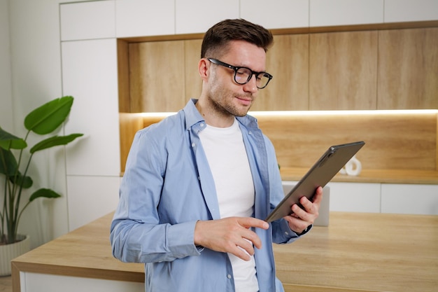 Focused and stylish a man examines his tablet in a modern airy home office natural light casting a soft glow