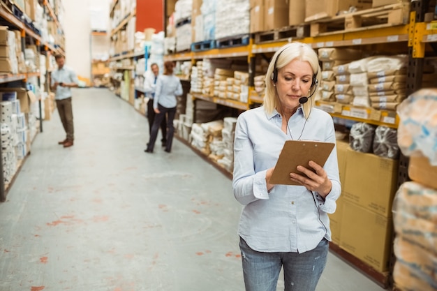 Focused warehouse manager writing on clipboard