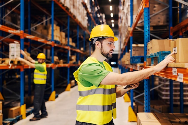 A focused warehouse worker looking at boxes for shipment