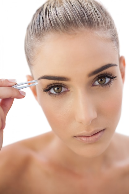 Focused woman plucking her eyebrows